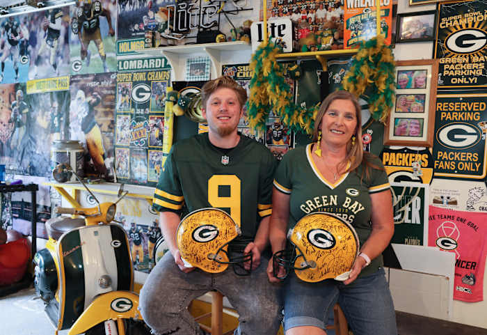 A portrait of Packers fans Philip and Sandy Gutting holding team helmets.